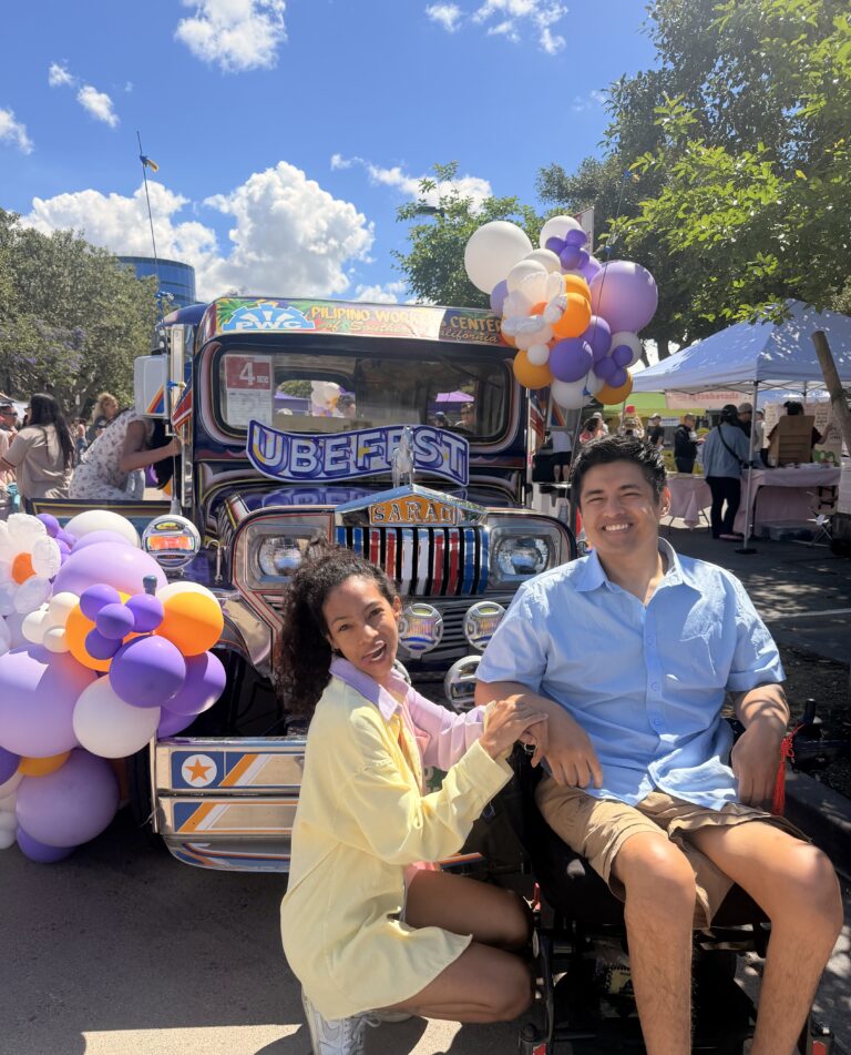 Cielo and Miguel holding hands beside a decorated jeepney with purple and gold balloons at a Filipino festival
