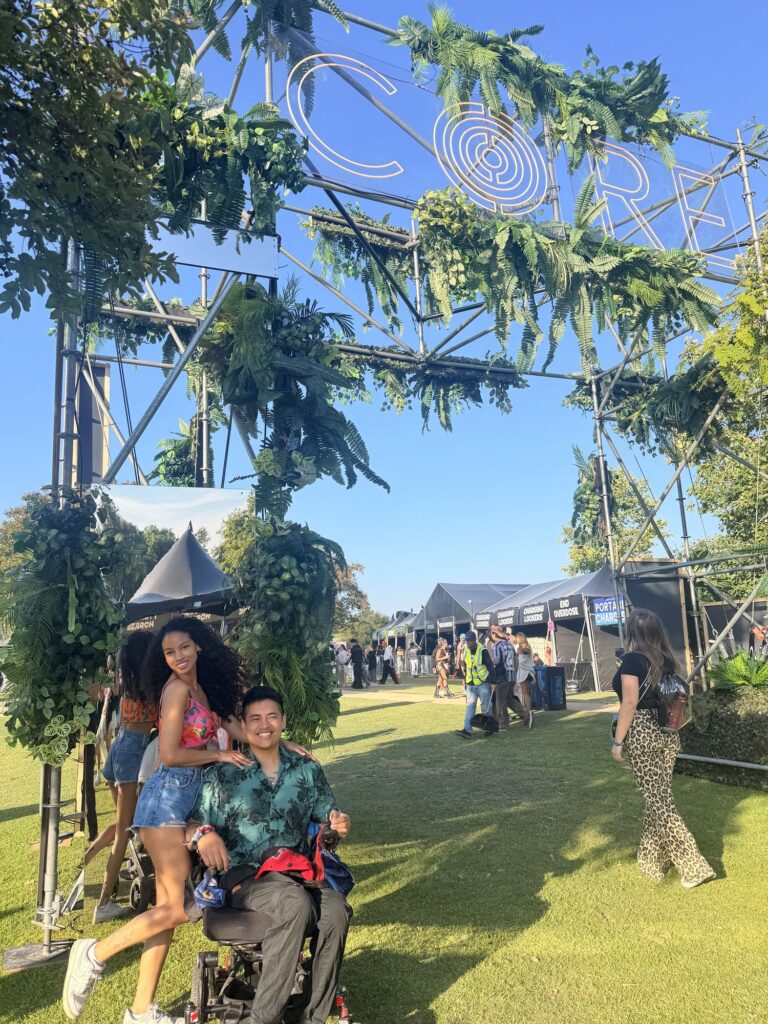 Cielo and Mike under a greenery arch on an outdoor festival lawn