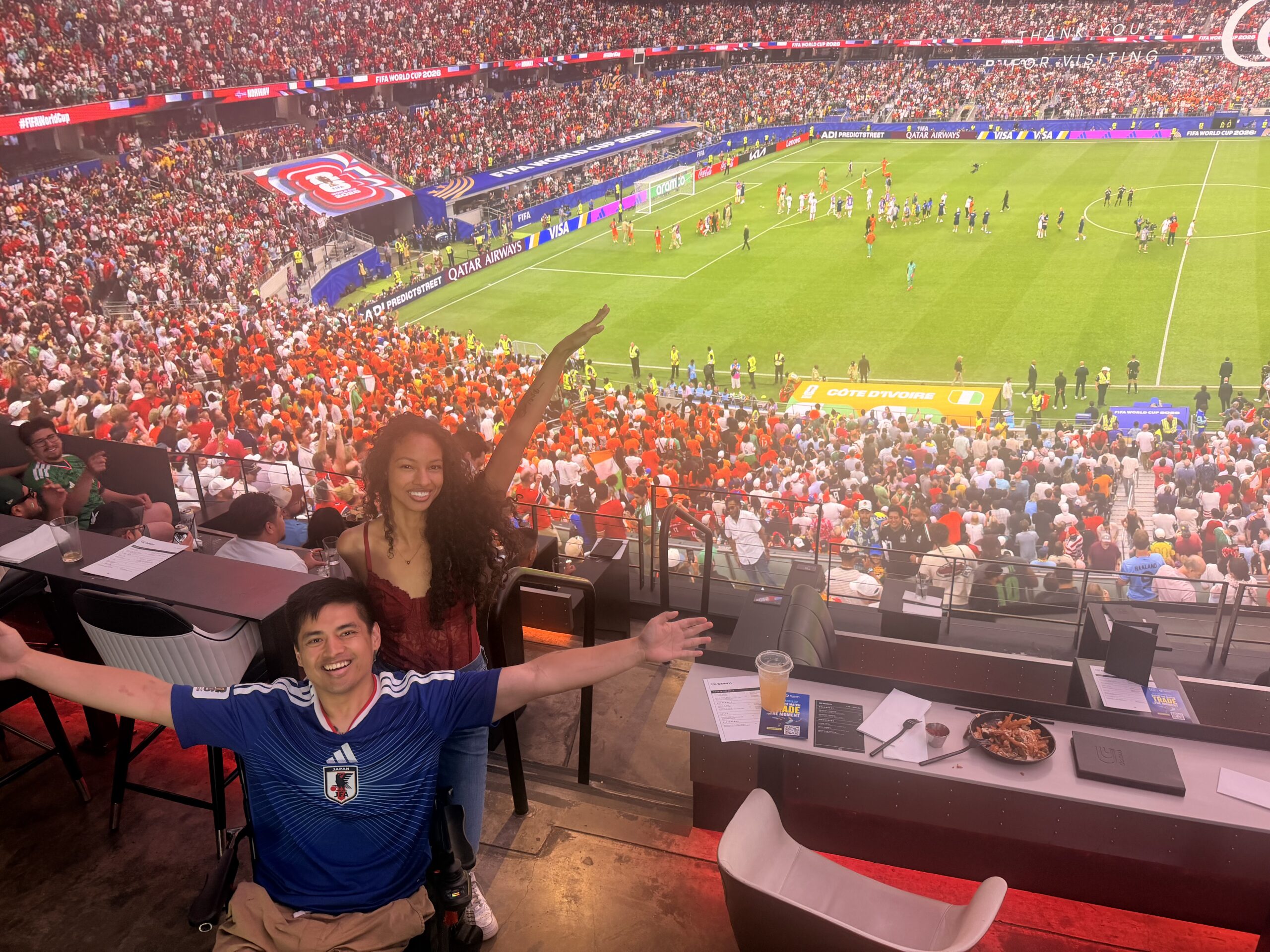 Cielo and Mike cheering from an accessible suite at a packed soccer stadium