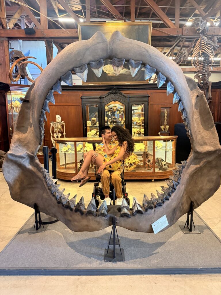 Cielo sitting on Mike's lap framed by a giant shark jaw at a curiosities museum