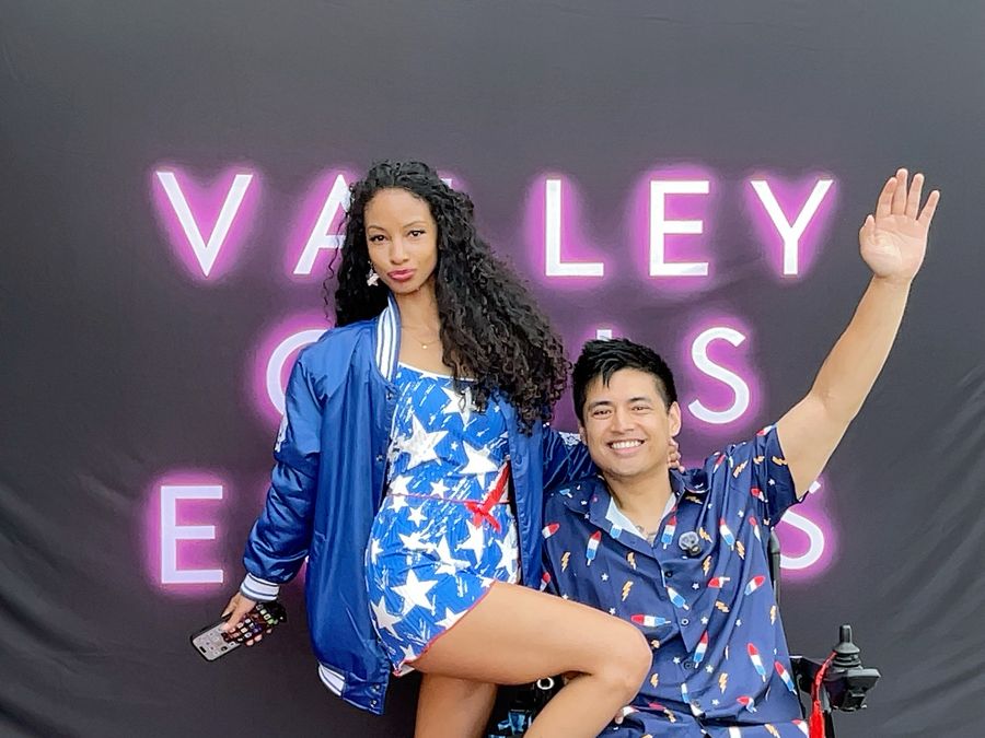 Cielo and Mike dressed up in front of a neon sign photo backdrop