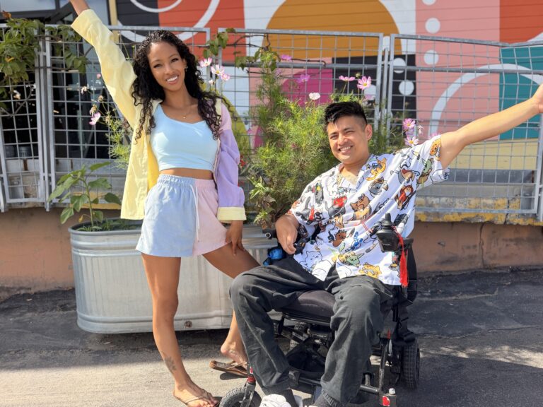 Cielo and Miguel striking playful poses on a rooftop patio with a mural behind them