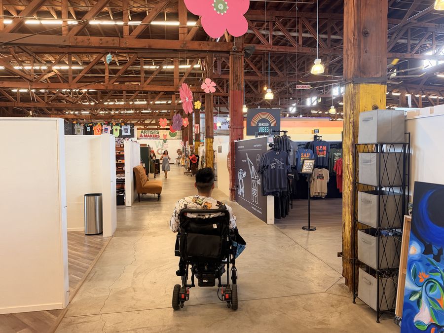 Mike browsing an indoor artisan market in his wheelchair