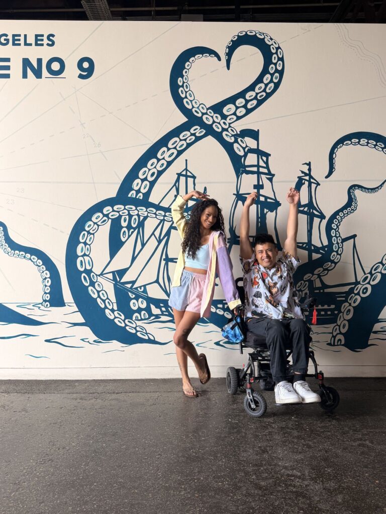 Cielo and Mike goofing around in front of a kraken and sailing ship mural