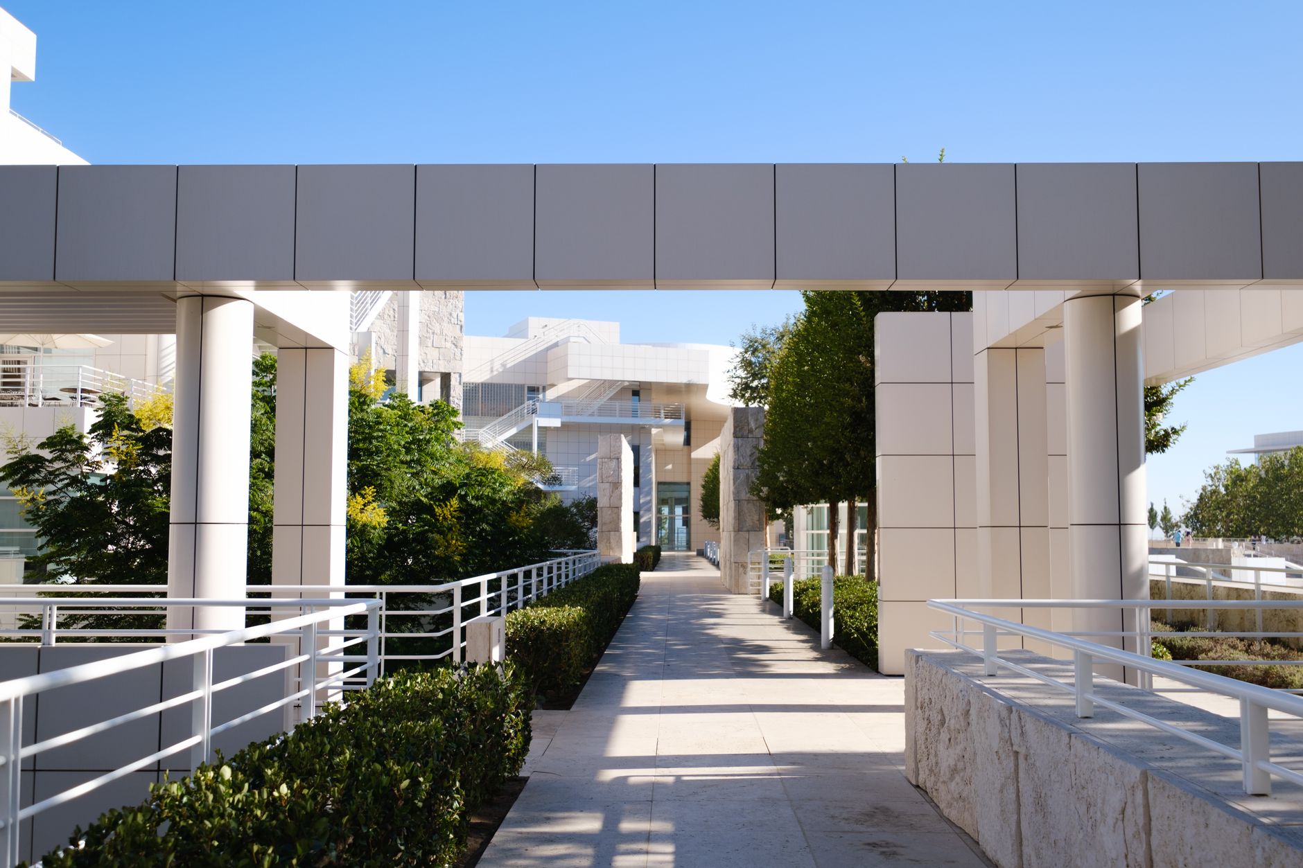 A level stone walkway between buildings at the Getty Center, with white handrails on both sides.