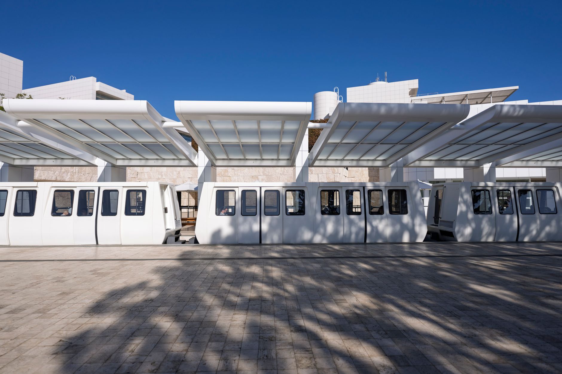White tram cars waiting with their doors open at the Getty Center tram station.