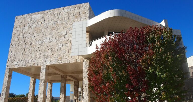 The travertine stone and white panel exterior of the Getty Center against a blue sky.