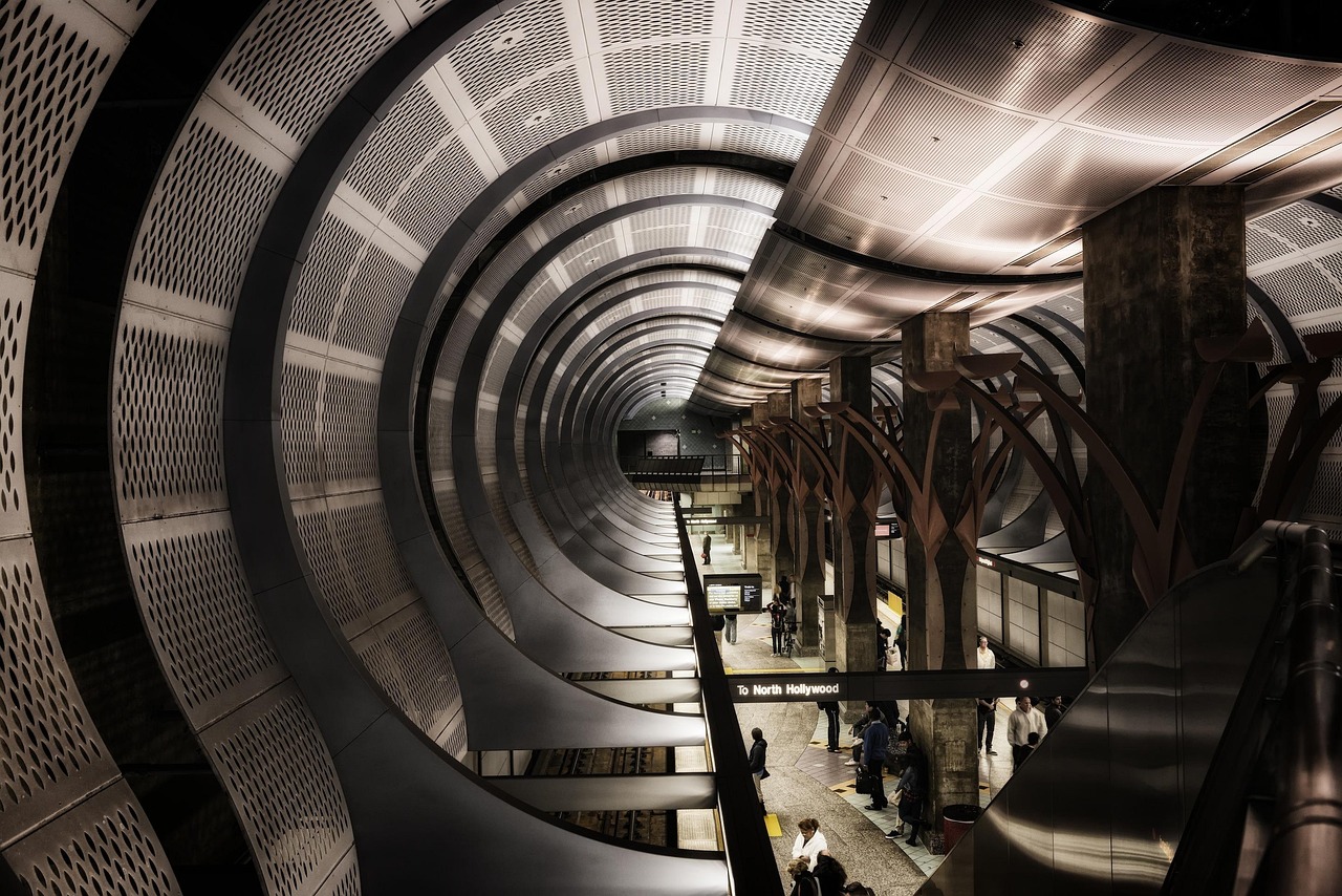 The curved ceiling and platform of a Los Angeles Metro station, with an escalator down to the trains.