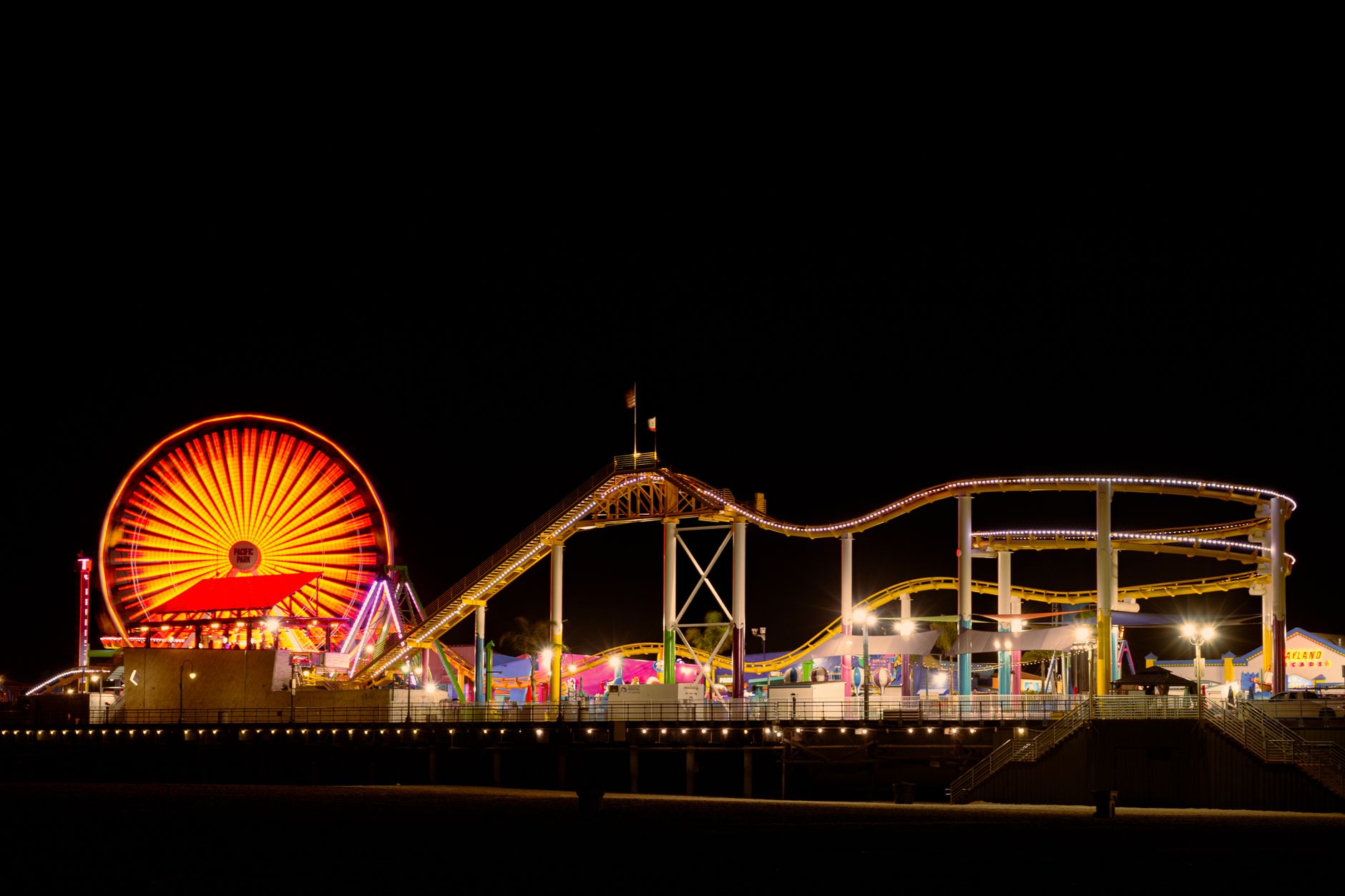 Pacific Park rides lit up on Santa Monica Pier after dark.