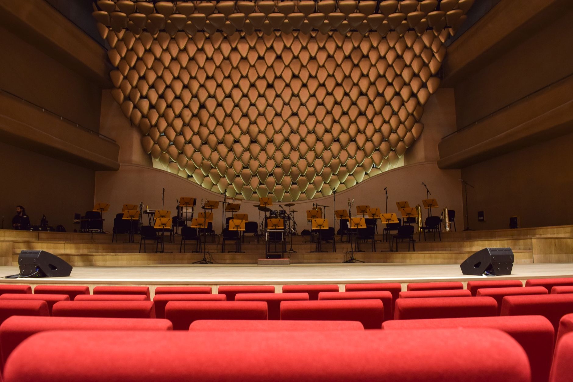 A concert hall interior with rows of empty red seats facing an empty stage