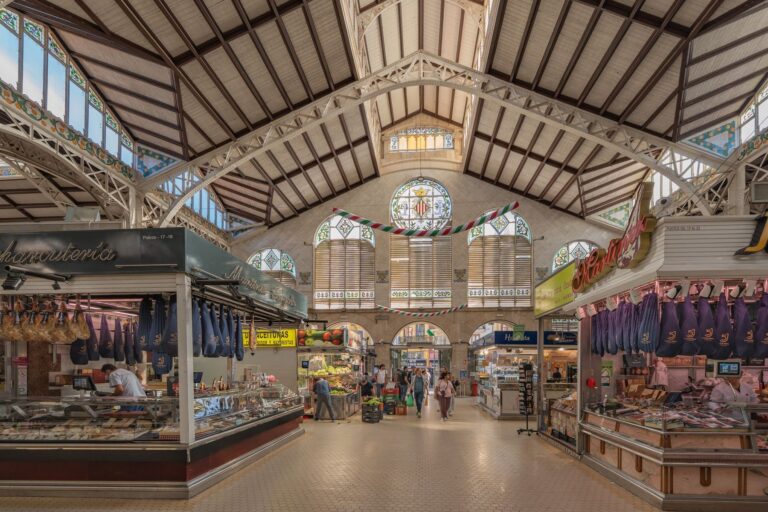 Interior of a covered food market hall with rows of vendor stalls under an arched roof