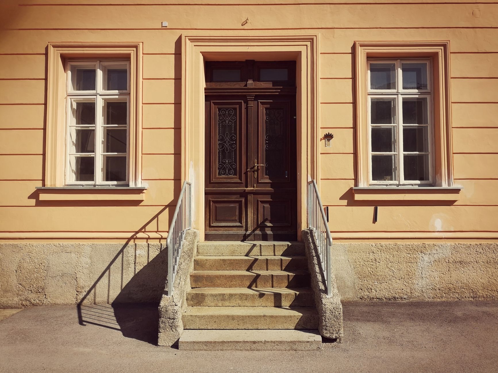 A restaurant doorway at the top of a short flight of stone steps with a metal handrail