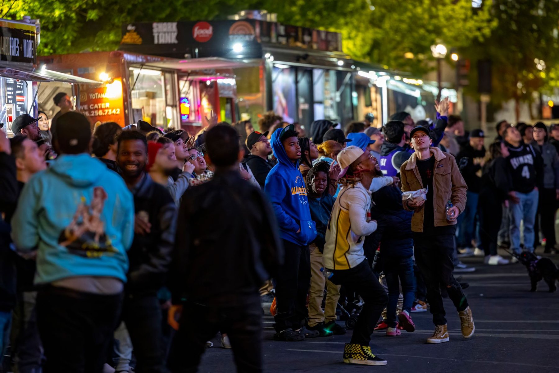 A dense crowd walking between lit food stalls at a night street festival