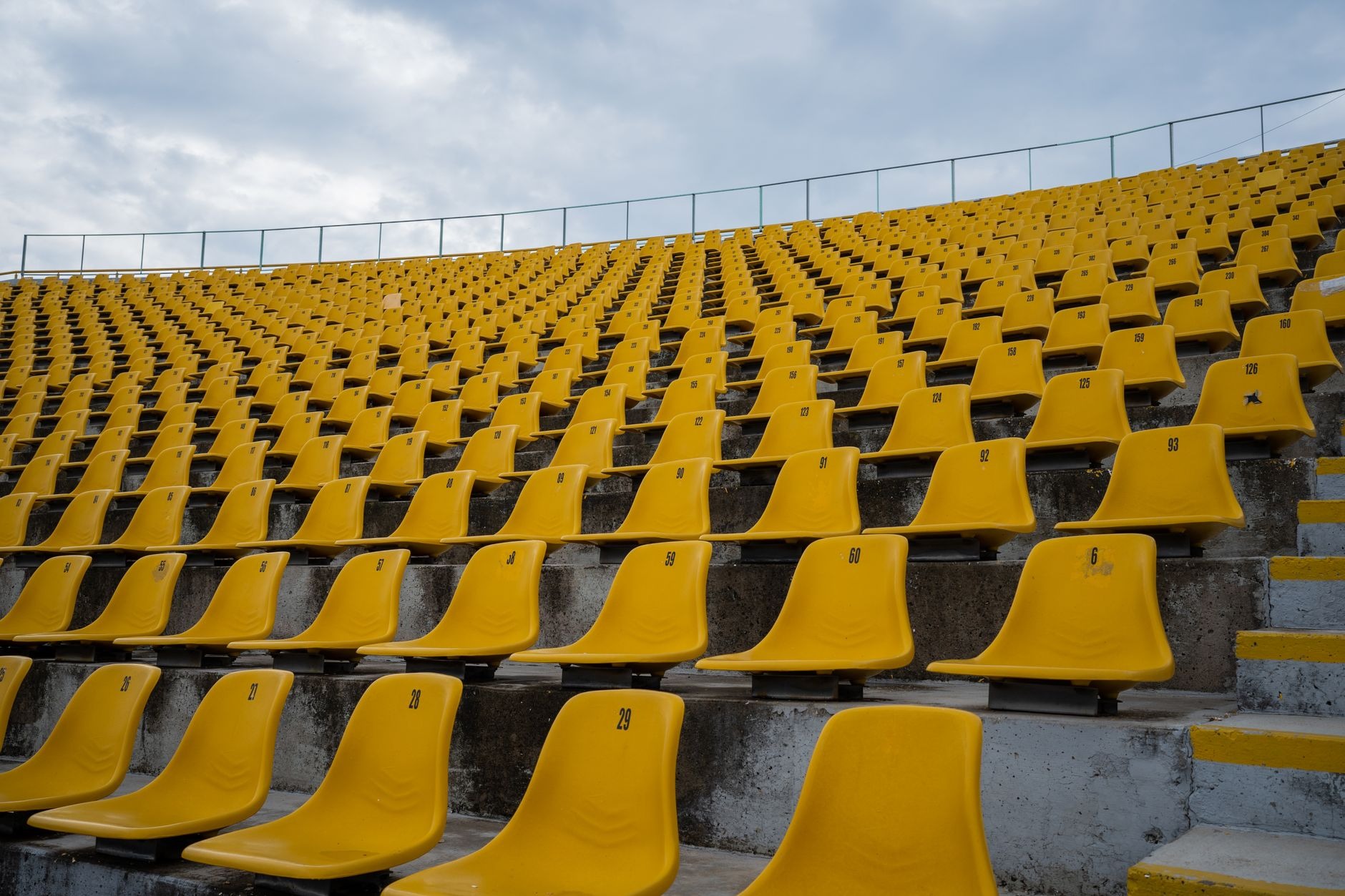 Rows of empty yellow stadium seats in full sun