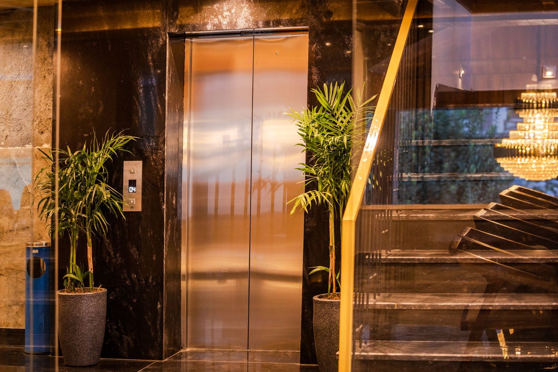An elevator door beside a staircase in a dimly lit lobby