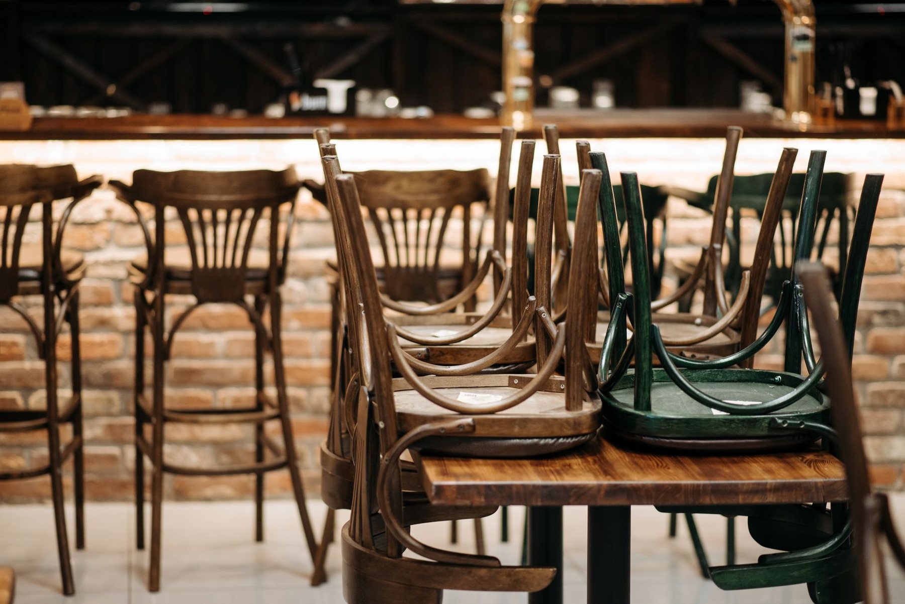 Chairs stacked upside down on tables in a closed bar at the end of the night
