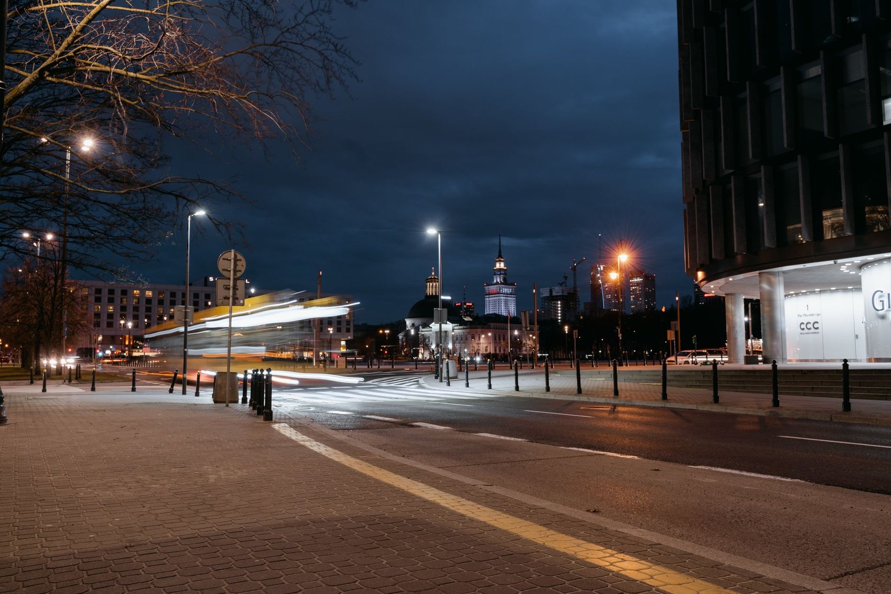 An almost empty city street late at night with light trails from passing traffic
