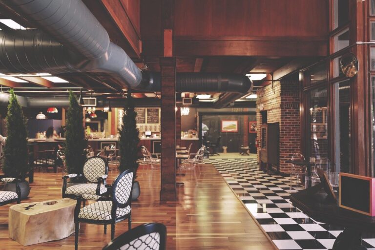 A wide view of a bar interior showing the layout, loose tables, a checkerboard floor and the bar counter at the back