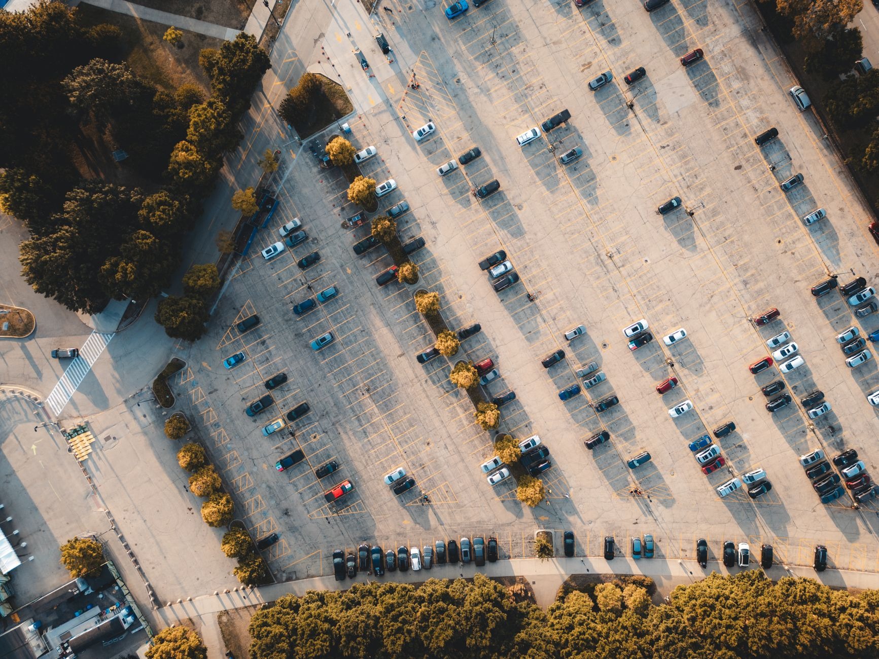 A top-down aerial view of a parking lot with cars in marked rows