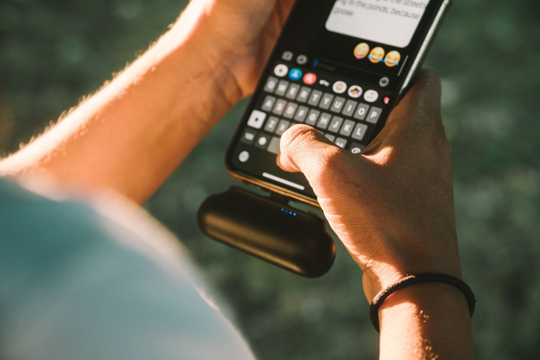 A hand holding a portable power bank plugged into a smartphone