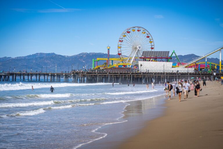Santa Monica Pier seen from the sand, with its Ferris wheel and roller coaster out over the water