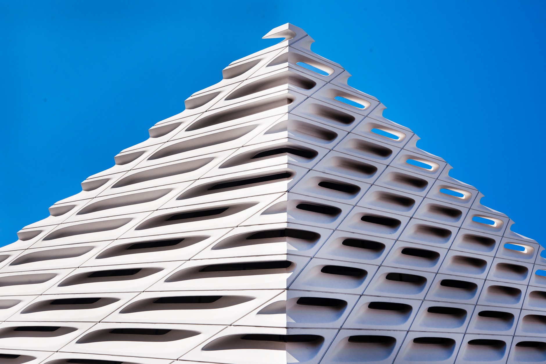 The honeycomb concrete facade of The Broad museum in downtown Los Angeles against a blue sky